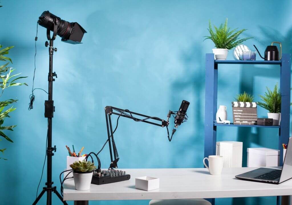 Professional light stand in empty, in-house mini video studio with microphone used for recording video marketing content. Recording setup with digital mixer console and laptop computer.